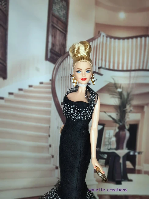 Poupée Barbie portant une robe de soirée longue en suédine noire avec volant en organza à pois blancs et paillettes.