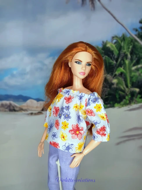Tenue artisanale en coton pour poupée : Haut floral et pantalon mauve | Violette-Créations Ensemble artisanal Violette-Créations composé d'un haut floral et d'un pantalon mauve en 100% coton pour poupée Barbie