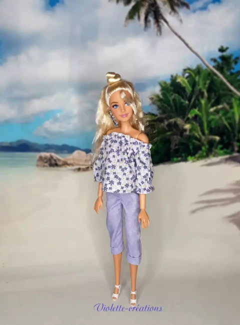 Poupée Chic : Ensemble en Coton Haut Floral et Pantalon Capri Lavande Poupée portant un ensemble en coton composé d'un haut à épaules dénudées à imprimé floral bleu et violet, d'un pantalon capri couleur lavande avec ourlets retroussés