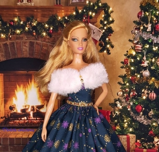 Poupée Barbie portant une robe de Noël bleu saphir avec motifs dorés et violets, accompagnée d'une étole en fausse fourrure blanche
