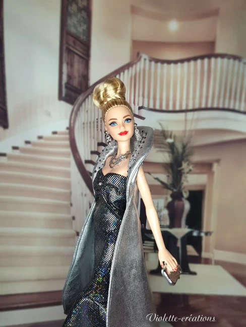 Poupée barbie portant une robe de soirée longue à paillettes avec cape argentée, dans un décor de grand escalier luxueux