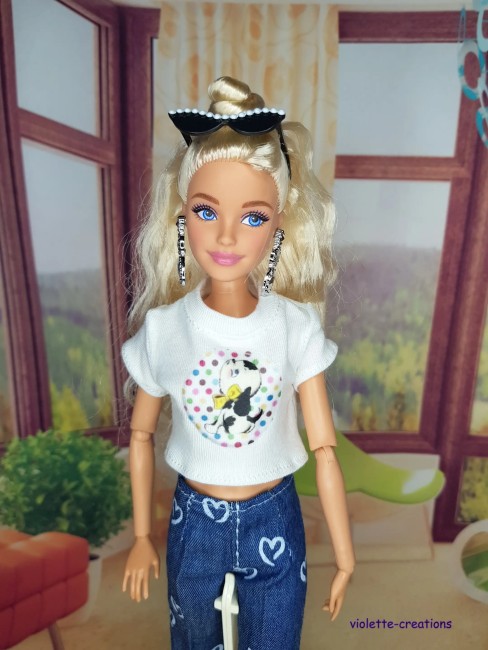 Tenue complĂšte vintage pour poupĂ©e Barbie â Jean Ă cĆurs, blouson papillons, maillot fushia PoupĂ©e Barbie portant un jean bleu Ă cĆurs, un maillot rose fushia, un blouson violet dĂ©corĂ© de papillons et un t-shirt Ă motif sous le blouson.