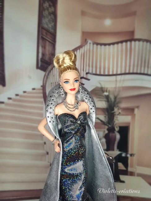 Poupée barbie portant une robe de soirée longue à paillettes avec cape argentée, dans un décor de grand escalier luxueux