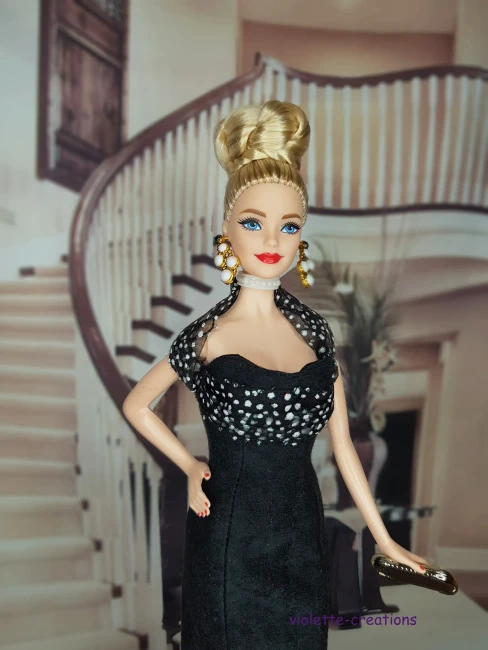 Poupée Barbie portant une robe de soirée longue en suédine noire avec volant en organza à pois blancs et paillettes.