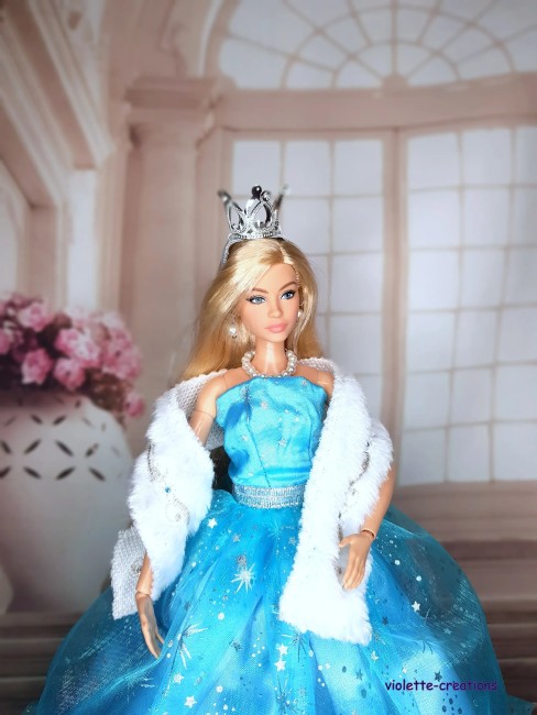 Robe de Princesse Bleu Étoilé pour Poupée barbie – Tenue Scintillante Poupée Barbie portant une robe bleu clair scintillante avec petites étoiles argentées, étole blanche, couronne et bijoux.