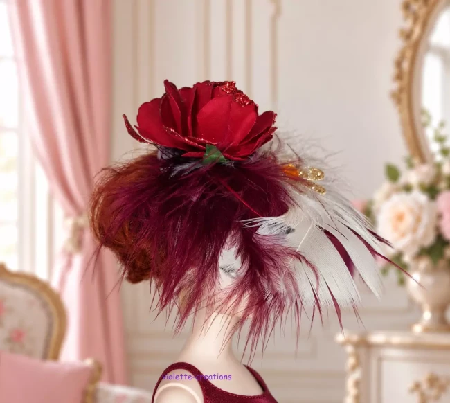 Chapeau bibi rouge pour poupée type barbie avec rose à paillettes, plumes bordeaux et blanches, et ornement doré.