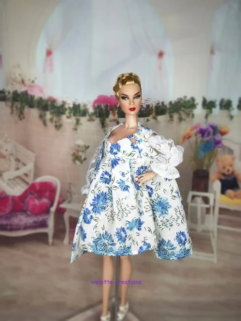 poupée Barbie portant une robe de chambre blanche à motif floral bleu avec des manches bouffantes en dentelle blanche et une nuisette assortie.