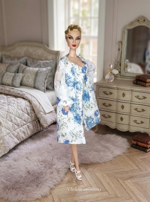 poupée Barbie portant une robe de chambre blanche à motif floral bleu avec des manches bouffantes en dentelle blanche et une nuisette assortie.