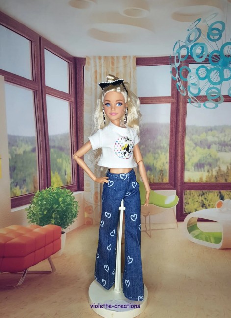 Tenue complĂšte vintage pour poupĂ©e Barbie â Jean Ă cĆurs, blouson papillons, maillot fushia PoupĂ©e Barbie portant un jean bleu Ă cĆurs, un maillot rose fushia, un blouson violet dĂ©corĂ© de papillons et un t-shirt Ă motif sous le blouson.