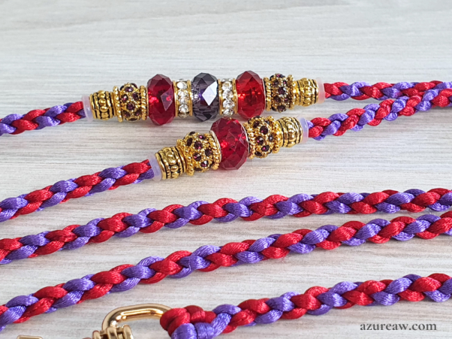 Gros plan sur les perles rouge rubis et violettes avec finitions dorées de la laisse Éclat Impérial