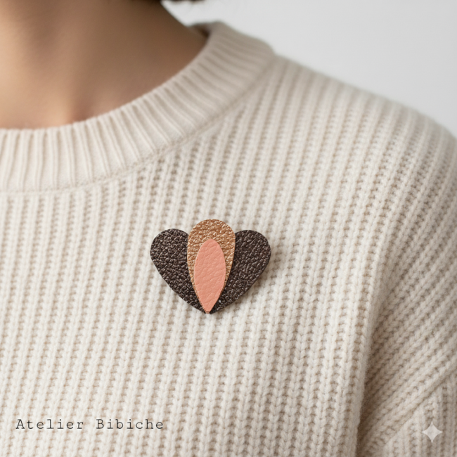 Broche en forme de cœur marron chocolat avec un motif central en forme de pétale de lotus, or rose cuivré et orange pêche.