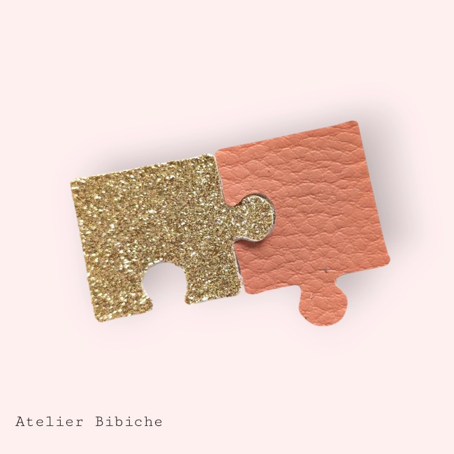 Broche Puzzle Fait Main - Pêche, Or Pailleté, Pop Art Léger Broche représentant deux pièces de puzzle assemblées : une pièce or pailleté et une pièce rose pêche texturé.