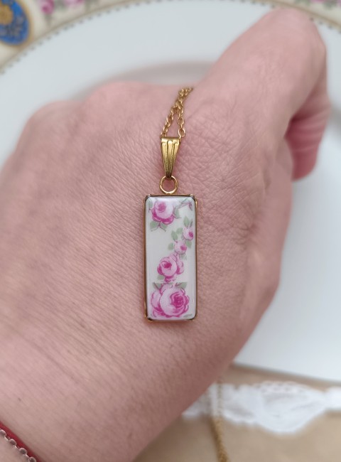 Collier en porcelaine de Limoges présenté en main pour visualiser son pendentif rectangulaire de 10 × 30 mm.
