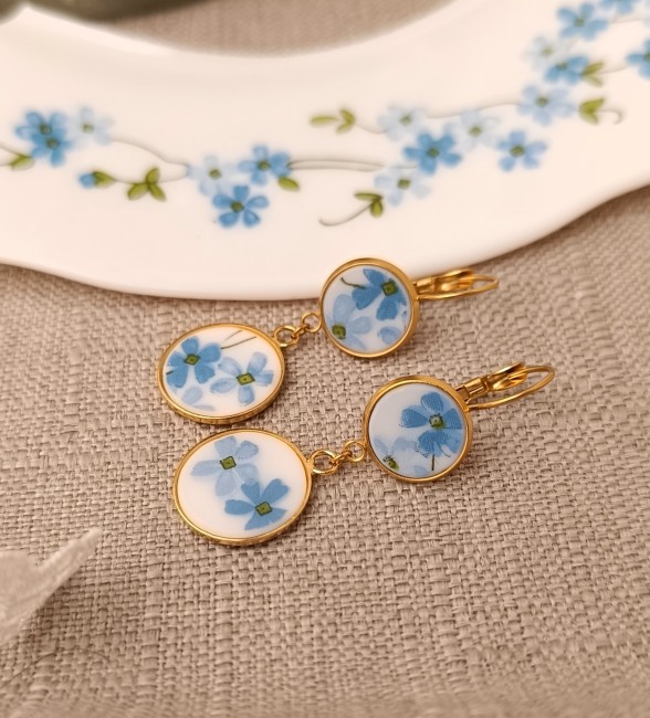 Détail du motif Myosotis en verre Arcopal, petites fleurs bleues sur double cabochon.