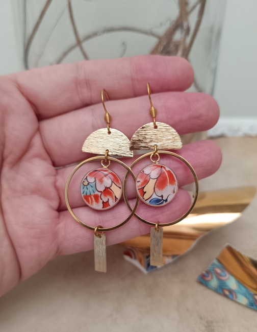 Boucles IMARI présentées en main pour apprécier leur longueur d'environ 60 mm et leur composition asymétrique.