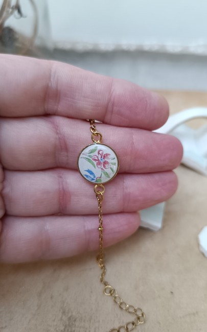 Bracelet présenté en main pour apprécier les dimensions et les détails du décor en faïence.