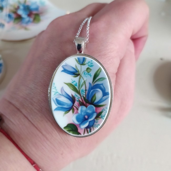 Collier Royal Tara tenu dans la main, détail du motif fleuri sur porcelaine irlandaise, bijou artisanal français fait main.