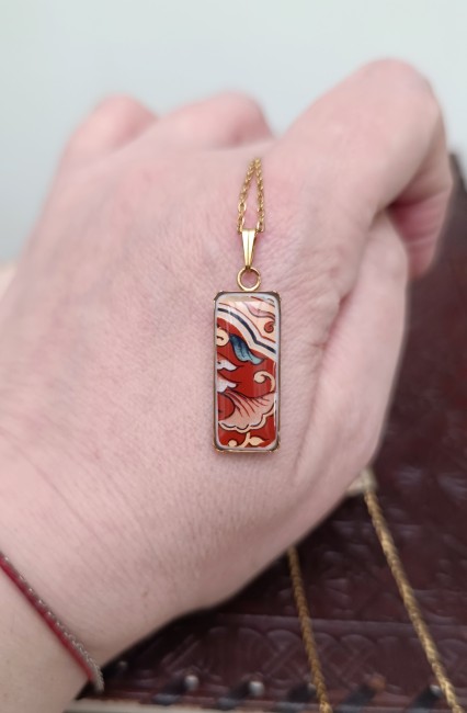 Collier au pendentif rectangualaire IMARI – Bijou unique en porcelaine japonaise de 1928 Collier IMARI tenu dans la main, bijou unique en porcelaine ancienne, montrant la délicatesse des fragments de porcelaine japonaise ancienne transformés en bijou contemporain.