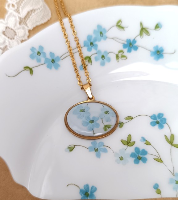 pendentif-ovale-horizontal-myosotis-fond-blanc Pendentif Myosotis en Arcopal recyclé sur fond blanc, monté sur support en acier inoxydable.