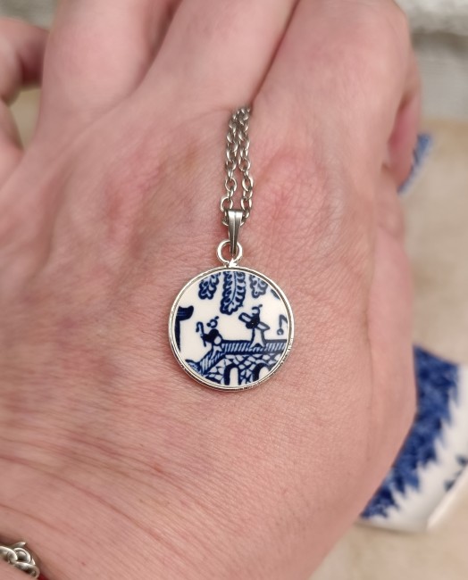 Collier présenté en main pour apprécier les dimensions du pendentif et les détails du motif Blue Willow.