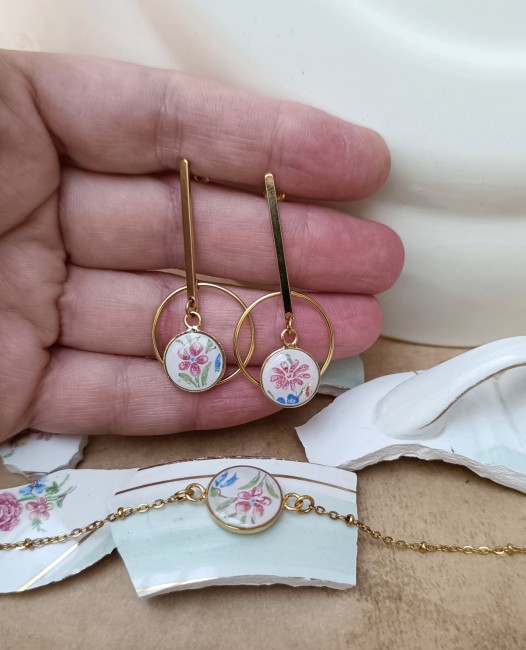 Boucles d'oreilles Céleste présentées en main pour apprécier les dimensions et les détails du décor d'origine.