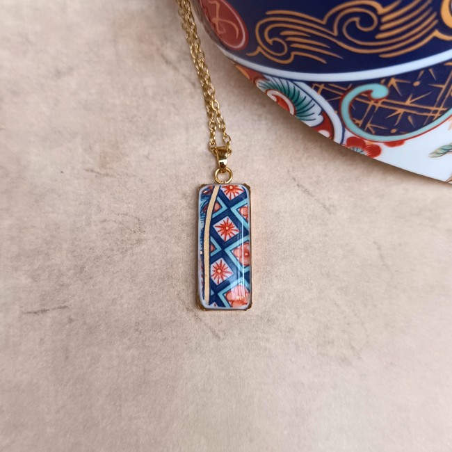 Détail du pendentif créé dans une ancienne théière japonaise en porcelaine, fragment scellé sous une résine transparente brillante.