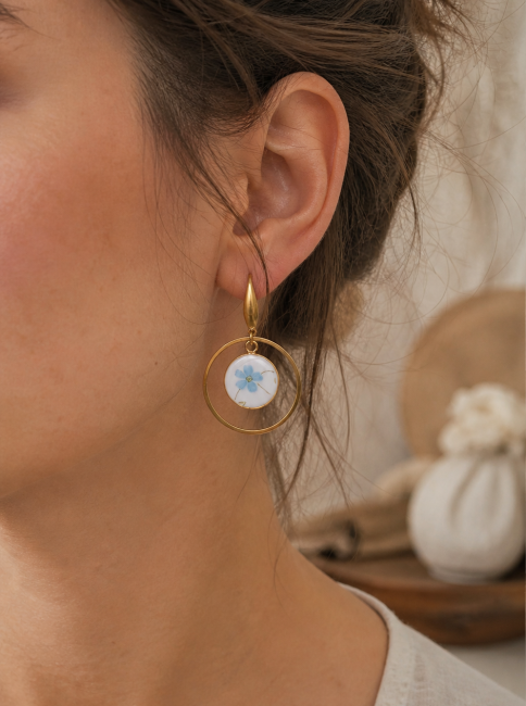 Boucles Myosotis portées, bijou en assiette recyclée aux fleurs bleues.