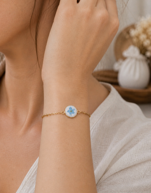 Bracelet Myosotis porté, bijou en assiette recyclée aux fleurs bleues.