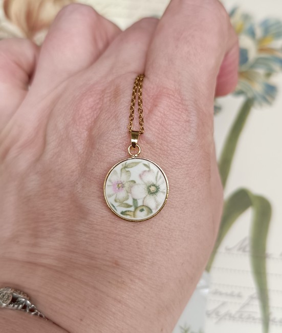Collier présenté en main pour apprécier les dimensions du pendentif et la finesse du décor Trianon inspiré du XVIIIᵉ siècle.