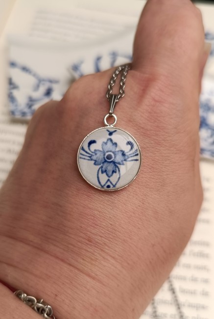 Collier artisanal présenté en main avec pendentif de 18 mm façonné dans une ancienne assiette en faïence française.