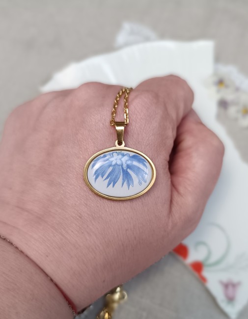 Collier présenté en main pour apprécier les dimensions du pendentif 30 × 20 mm et les détails du motif bleuet.