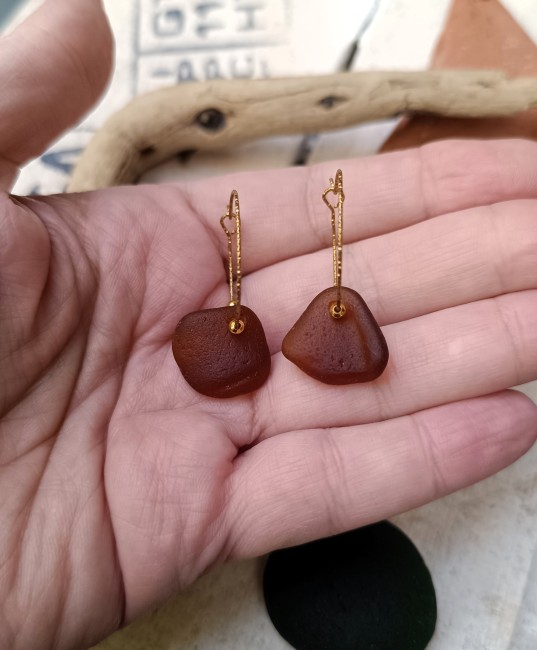 Zoom sur le verre de mer brun aux reflets ambre, poli naturellement par le sable et le temps.