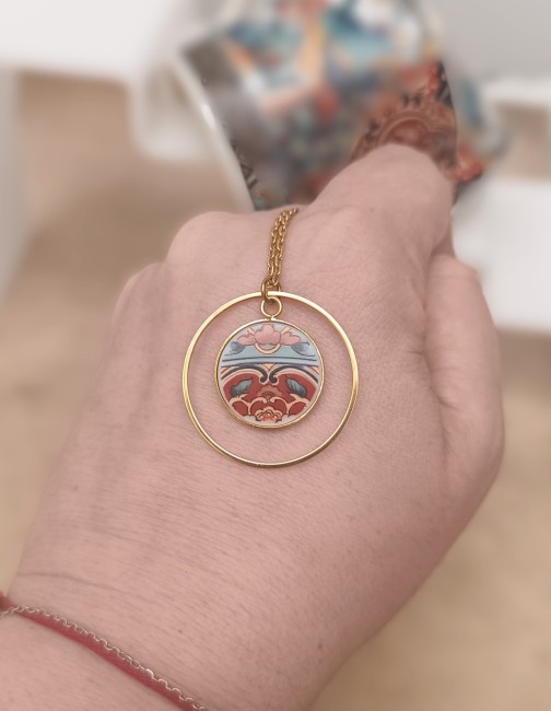 Collier IRAMI tenu à la main, montrant la délicatesse des fragments de porcelaine japonaise ancienne transformés en bijou contemporain.