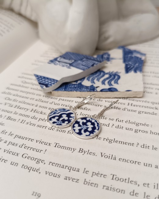 Boucles d’oreilles Blue Willow  en porcelaine posée sur un fond clair, modèle dormeuses en argent.