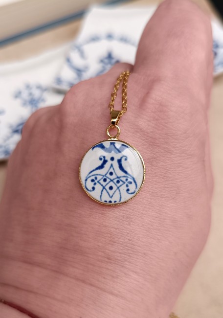 Photo du collier en faïence de Moustiers présenté dans son écrin. Pendentif rond 18 mm, création artisanale française à partir d’une assiette ancienne upcyclée.