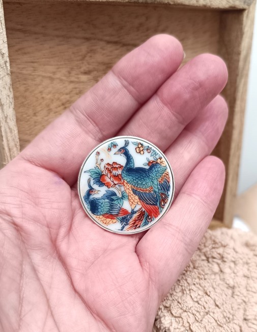 Gros plan sur le motif de paon de la broche Irami, issue d’une porcelaine japonaise ancienne transformée en bijou poétique.