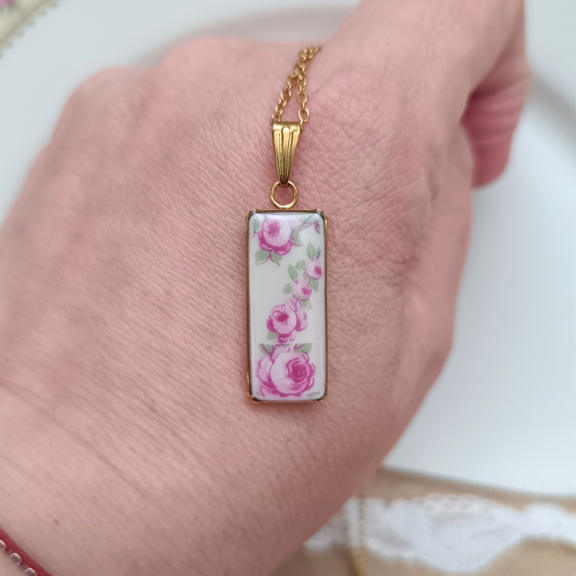 Collier en porcelaine de Limoges présenté en main pour visualiser son pendentif rectangulaire de 10 × 30 mm.