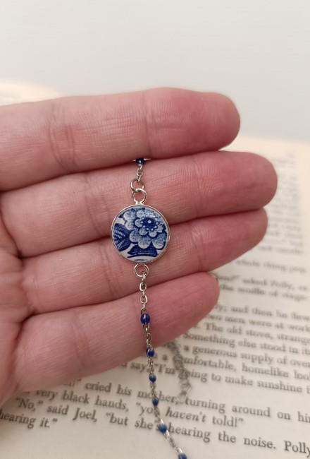 Bracelet présenté en main pour apprécier les dimensions, les détails du décor fleuri bleu et la finesse du travail artisanal.