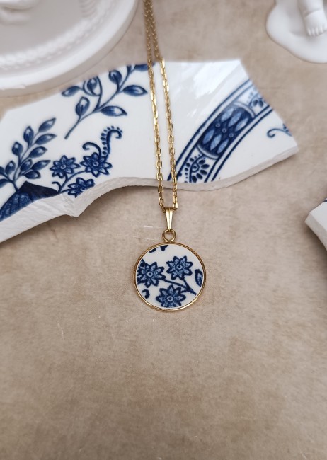 collier-bleu-vintage-porcelaine-anglaise-18mm-plaque-or Découvrez le collier Bleu Vintage, pièce unique en porcelaine anglaise ancienne, posé pour mettre en valeur son motif fleuri bleu sur fond blanc.