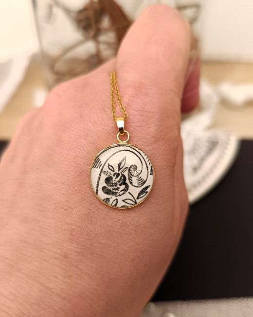 Collier Sonate présenté en main pour apprécier son pendentif de 18 mm en véritable faïence ancienne.