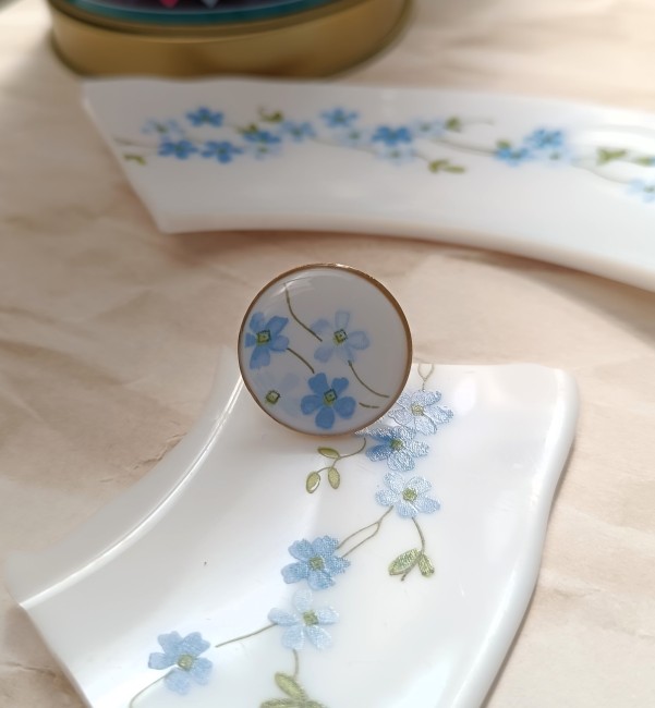 Détail du motif Myosotis en verre Arcopal, petites fleurs bleues et feuillage graphique.