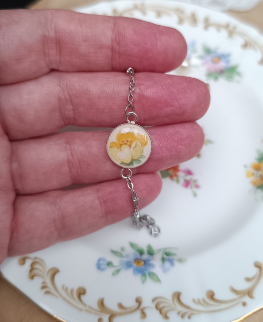 bracelet-poesie-main-details-roses-jaunes.jpg Bracelet Poésie présenté en main pour apprécier les proportions du cabochon de 14 mm et les détails du délicat motif floral.