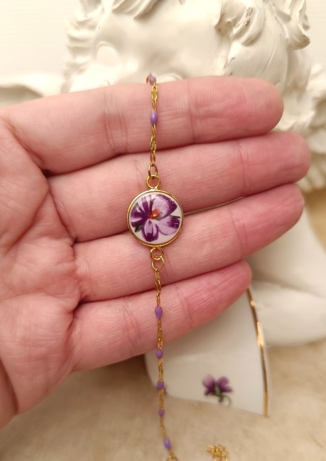 Gros plan sur le cabochon en porcelaine de Limoges, motif pensée mauve, création artisanale française unique.