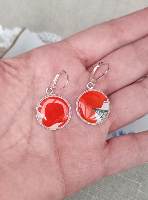 Boucles d'oreilles présentées en main pour apprécier les détails du motif et la finesse de la faïence ancienne.
