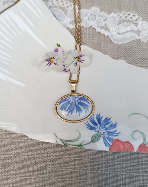 Collier Bleuet réalisé à partir d'une véritable faïence ancienne L'Amandinoise, décor historique n° 8962, monté sur un pendentif ovale horizontal en acier inoxydable doré.