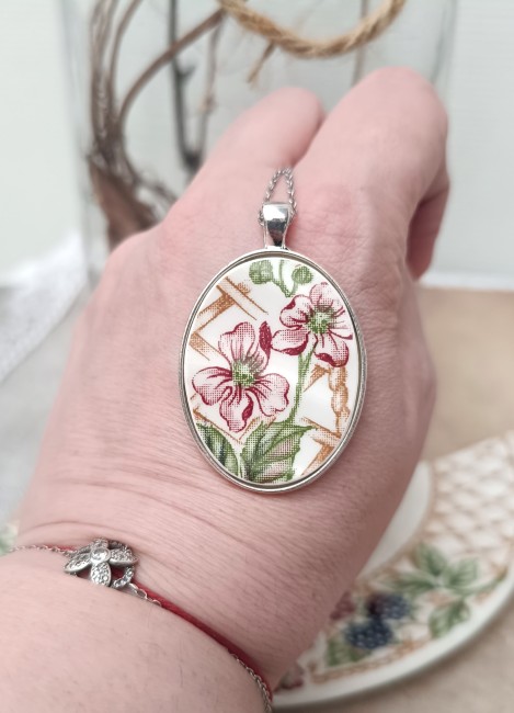 Collier jardin d'hiver, tenu dans la main, bdétails du motif fleuri.