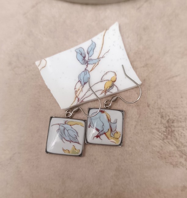 Boucles OPUS carrées réalisées à partir de porcelaine fine recyclée, décor floral bleu et jaune et finition résine brillante.