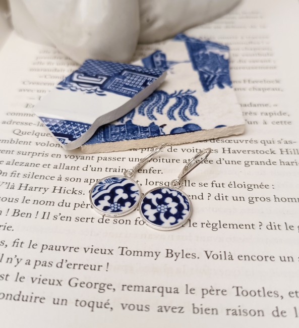 Boucles d’oreilles Blue Willow  en porcelaine posée sur un fond clair, modèle dormeuses en argent.