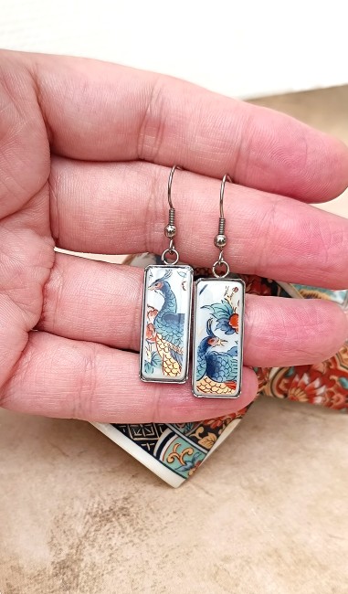 Boucles IRAMI tenues à la main, montrant la délicatesse des fragments de porcelaine japonaise ancienne transformés en bijou contemporain.