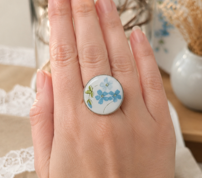 Détail du motif Myosotis en verre Arcopal, petites fleurs bleues et feuillage graphique.